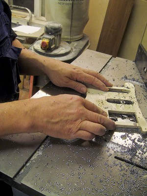 Routing the pickup holes flush with the template on a table router.