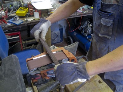 I often use a belt sander with a 150 grit belt to crude dress the frets and a file to finish the work.