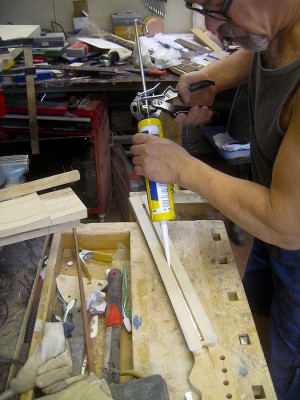 Time to install the one-way truss rod. Squeezing silicone caulk into the rod channel prior to installation to fix the rod and to prevent rattling later. There is masking tape on both sides of the channel to keep the caulk off all surfaces that will be glued later.