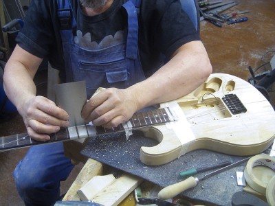 I use a common rectangular scraper as a fret rocker. Works fine.