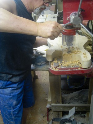 Prior to routing body cavities I remove most of the wood with a forstner bit on a drill press. Neck pocket being drilled.