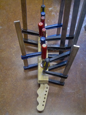 Gluing the fretboard to the neck takes a radiused caul and an army of clamps. The clamps obey orders and stay on their posts overnight.